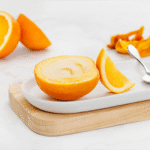 Sorbet Mango Orange Island Way en coque d’orange, mis en scène sur planche en bois clair