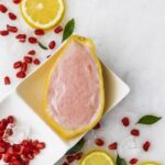 Sorbet Pomegranate Lemon Island Way dans sa coque de citron, entouré de graines de grenade, tranches de citron et glaçons